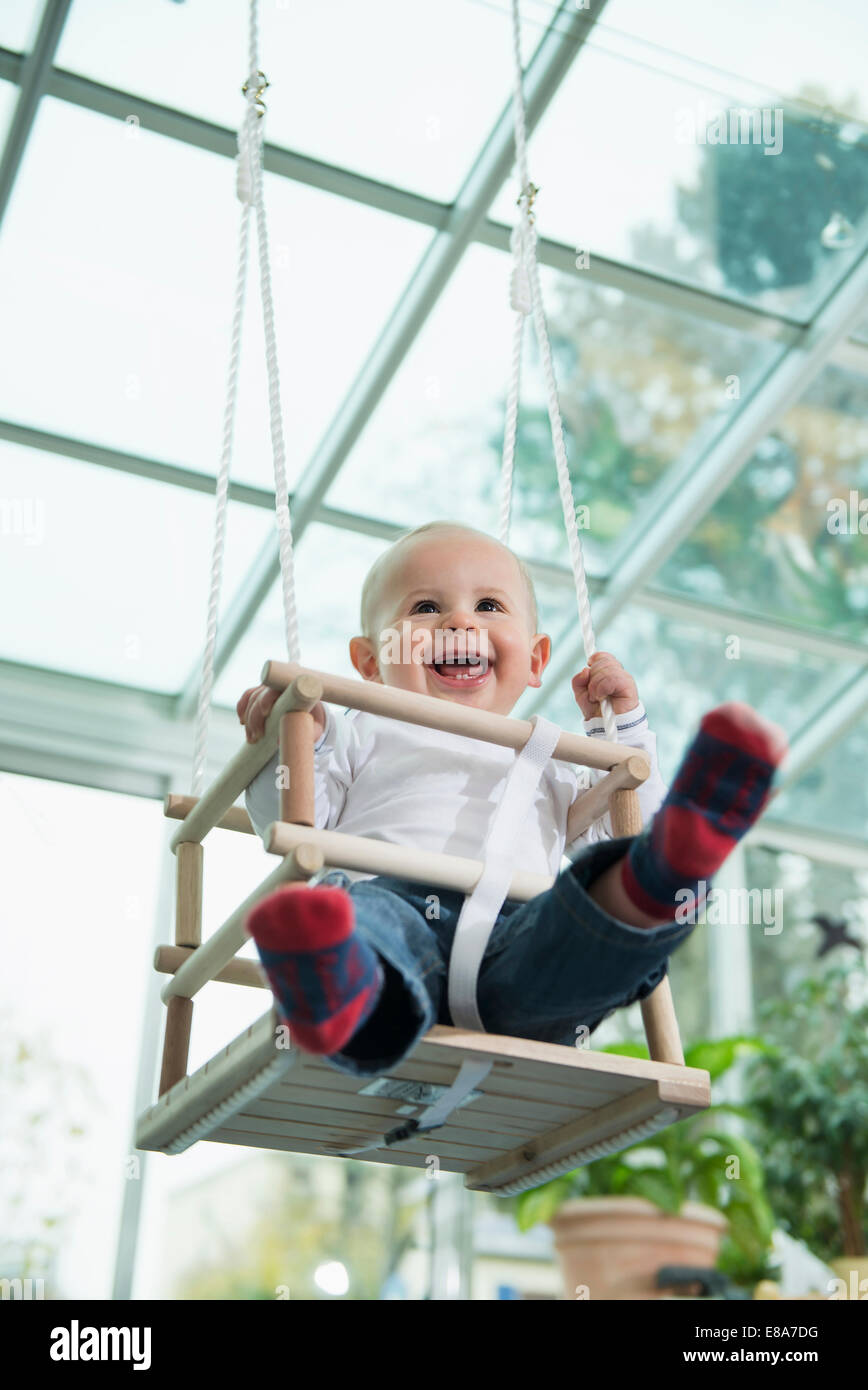 Portrait of laughing toddler sitting in a swing Banque D'Images
