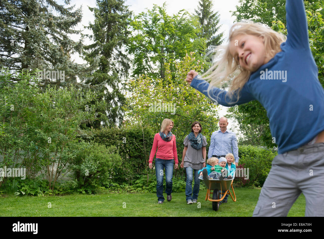 Jeune famille jouant dans jardin avec brouette Banque D'Images