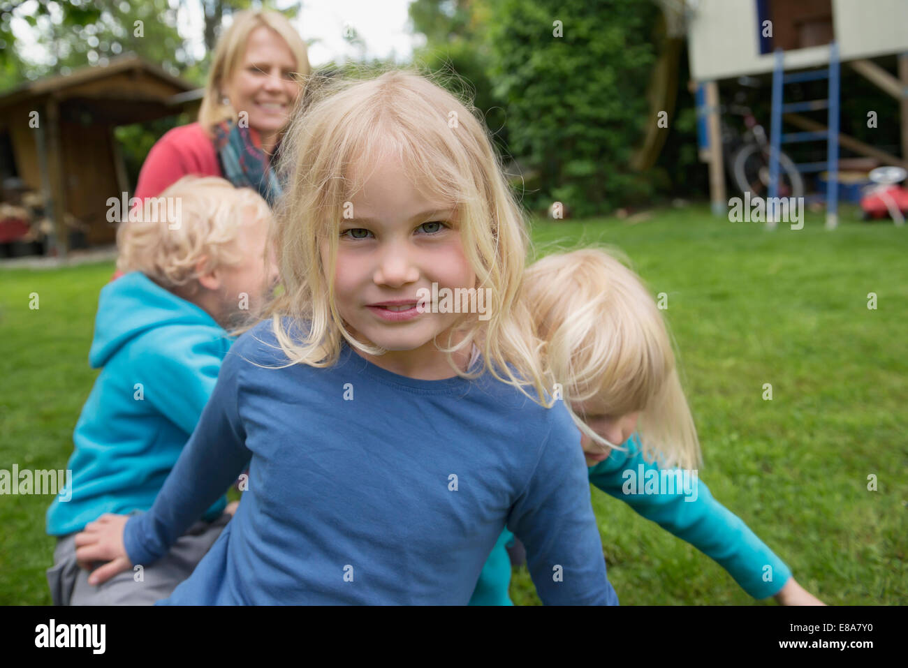 Mère jouant avec trois jeunes enfants dans jardin Banque D'Images