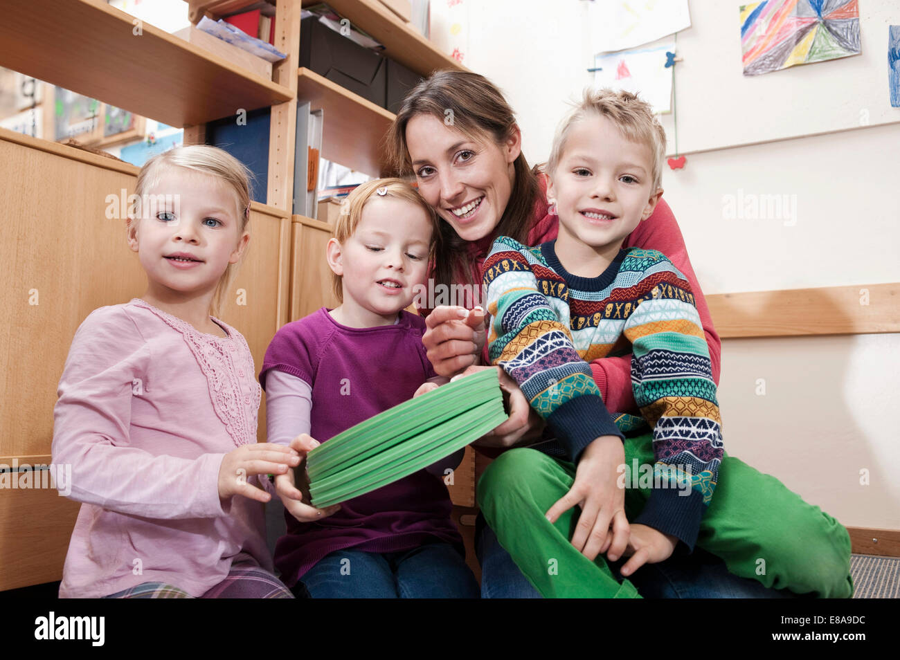 Photo de groupe des femmes d'éducateur et de trois enfants en maternelle Banque D'Images