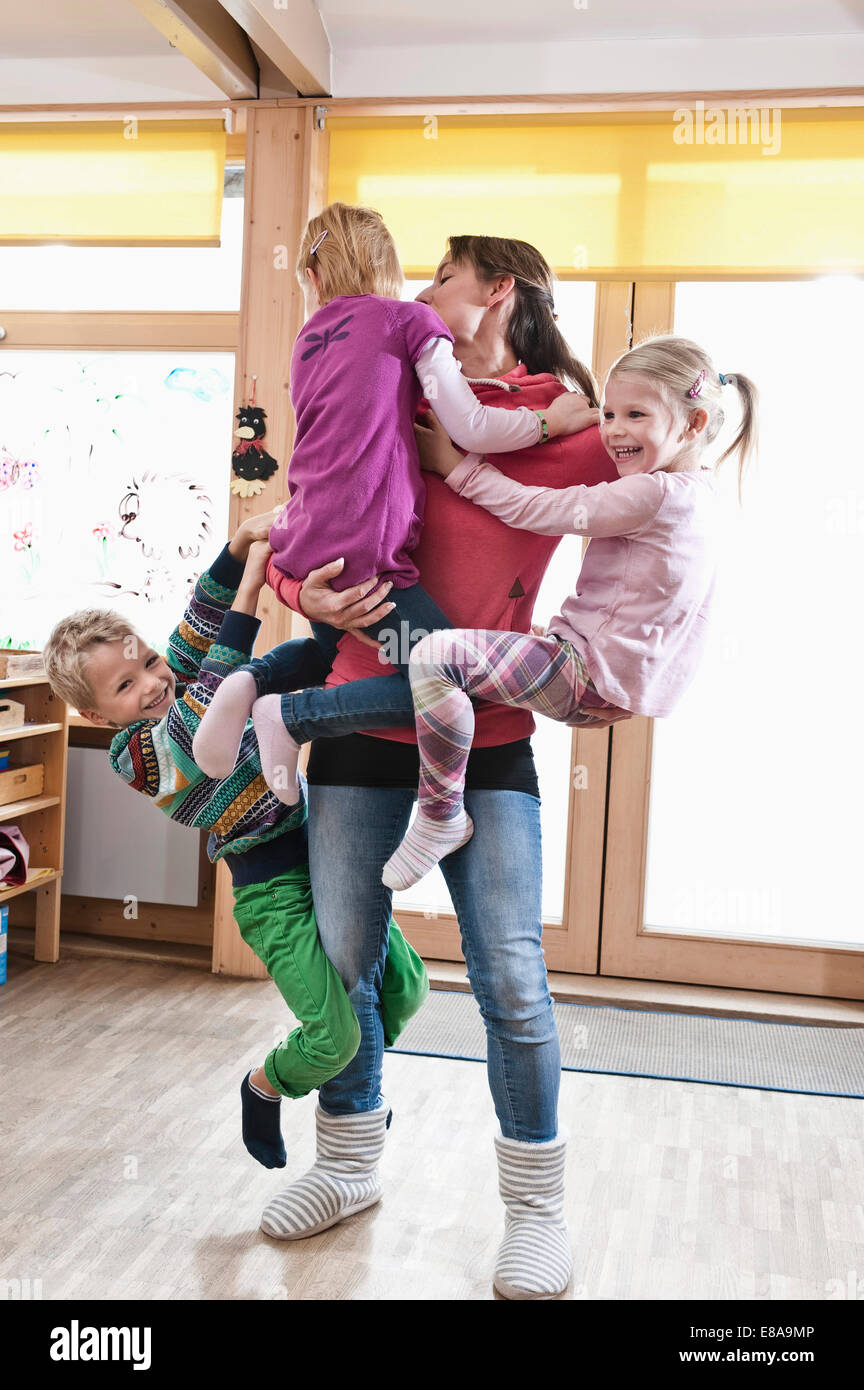 Éducateur femelle rampaging avec trois enfants en maternelle Banque D'Images