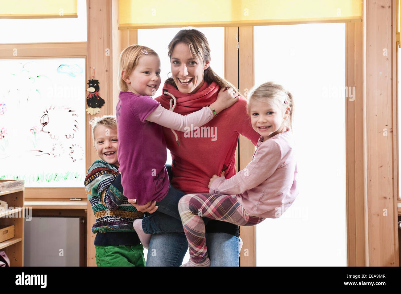 Éducateur femelle rampaging avec trois enfants en maternelle Banque D'Images