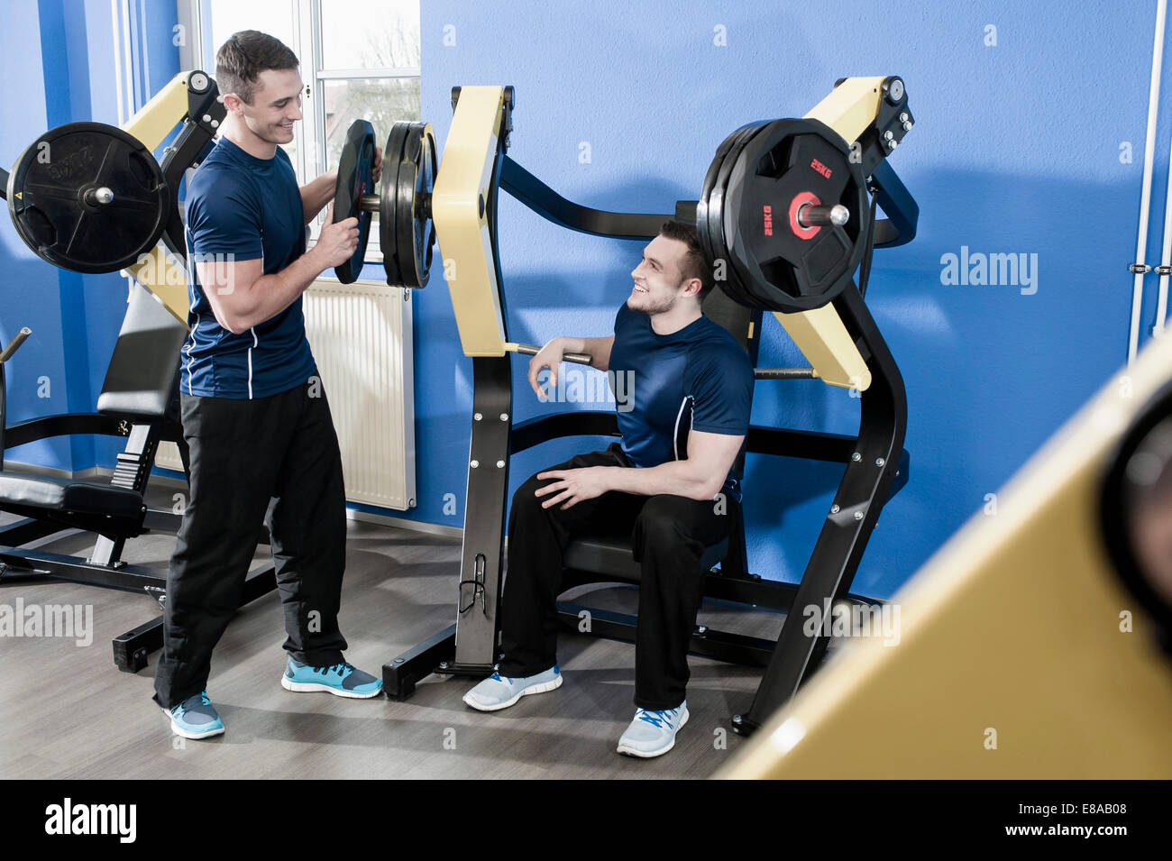 Deux jeunes hommes dans une salle de sport faire la formation de poids Banque D'Images