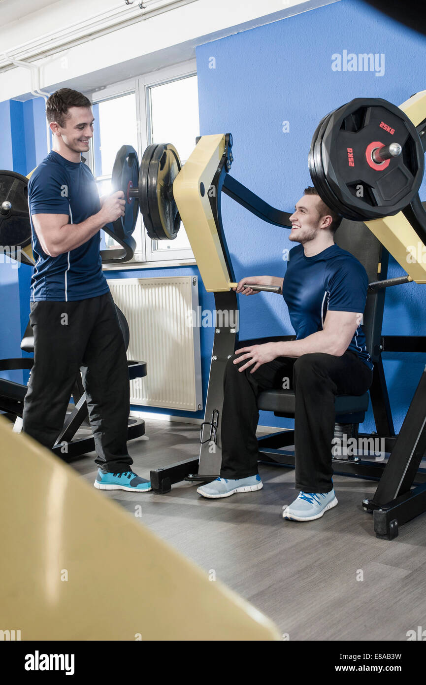 Deux jeunes hommes dans une salle de sport faire la formation de poids Banque D'Images