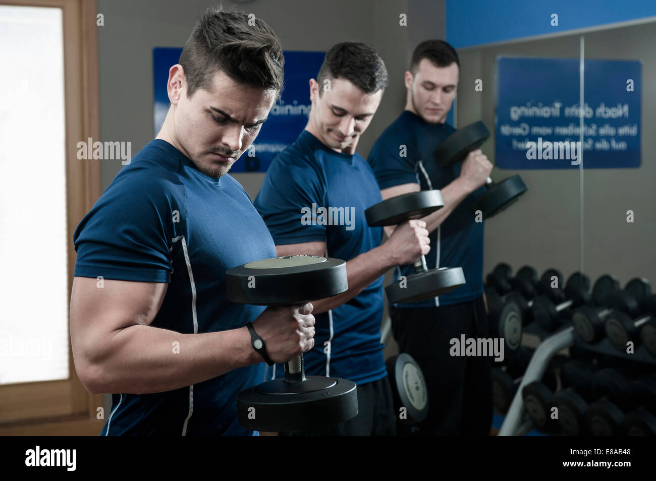 Trois jeunes hommes faisant la formation de poids dans une salle de sport Banque D'Images