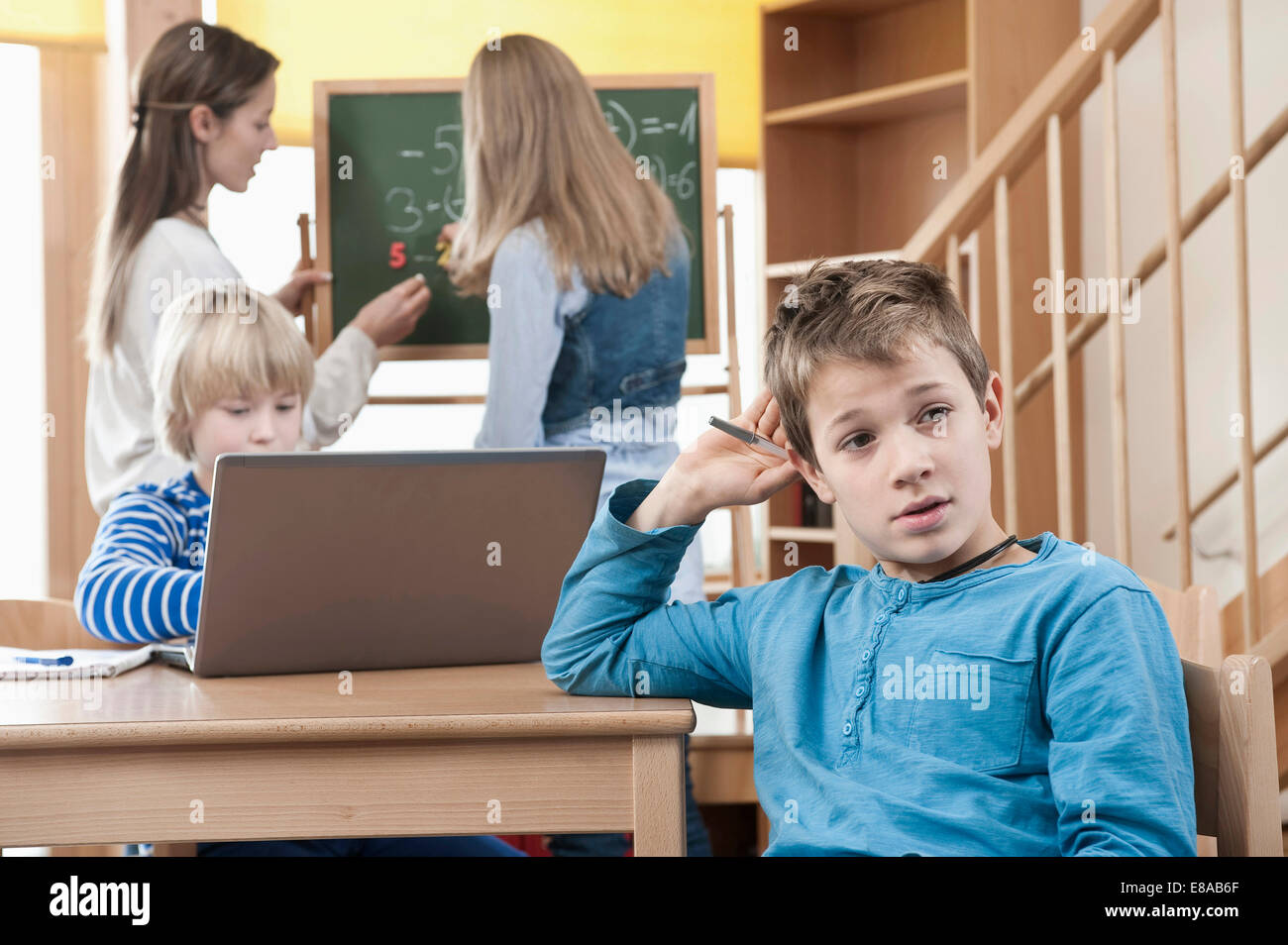 Assistant de garde d'aider les enfants de sexe féminin par faire leurs devoirs Banque D'Images