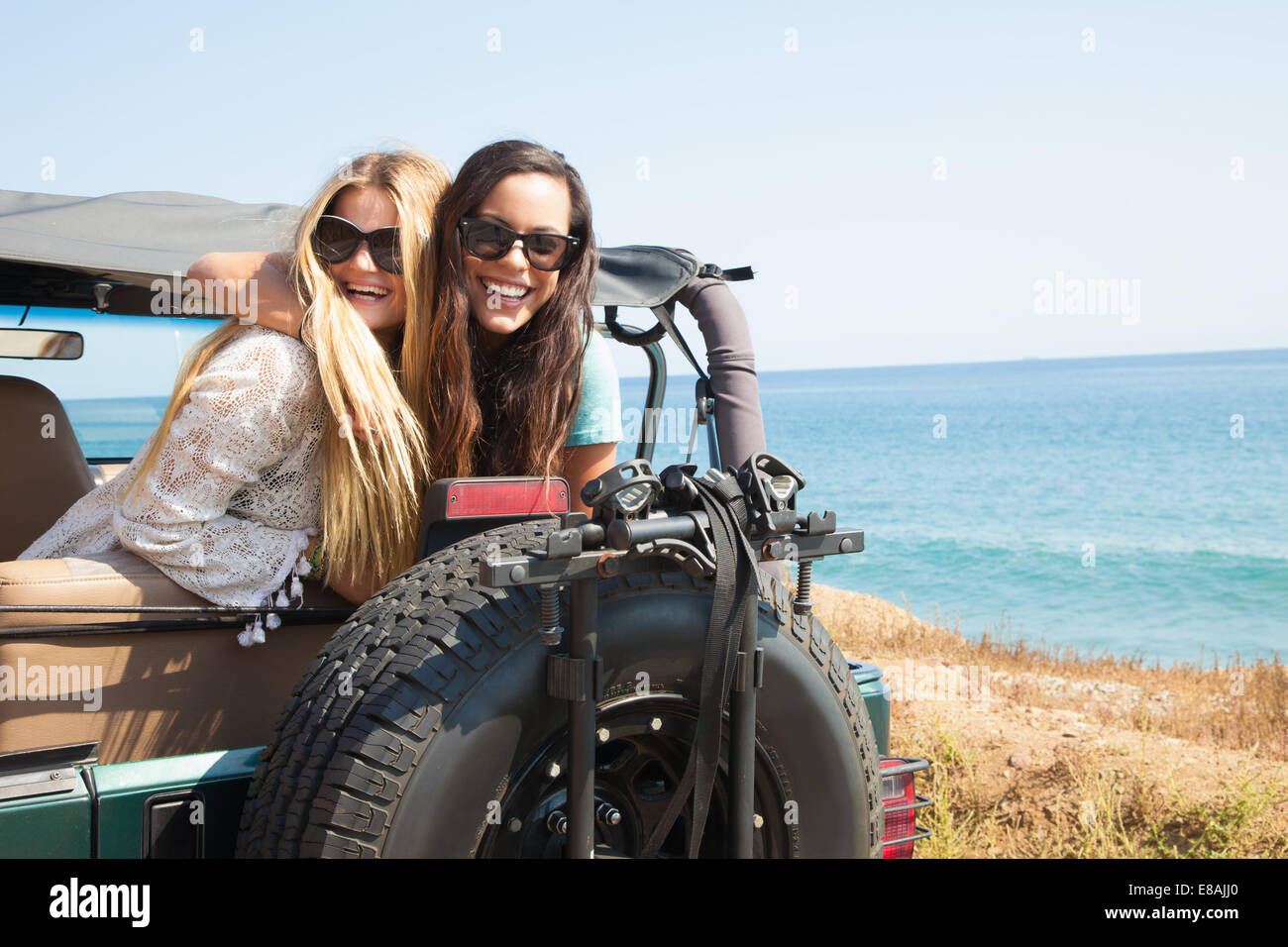 Portrait de deux jeunes femmes penché de jeep à côte, Malibu, California, USA Banque D'Images