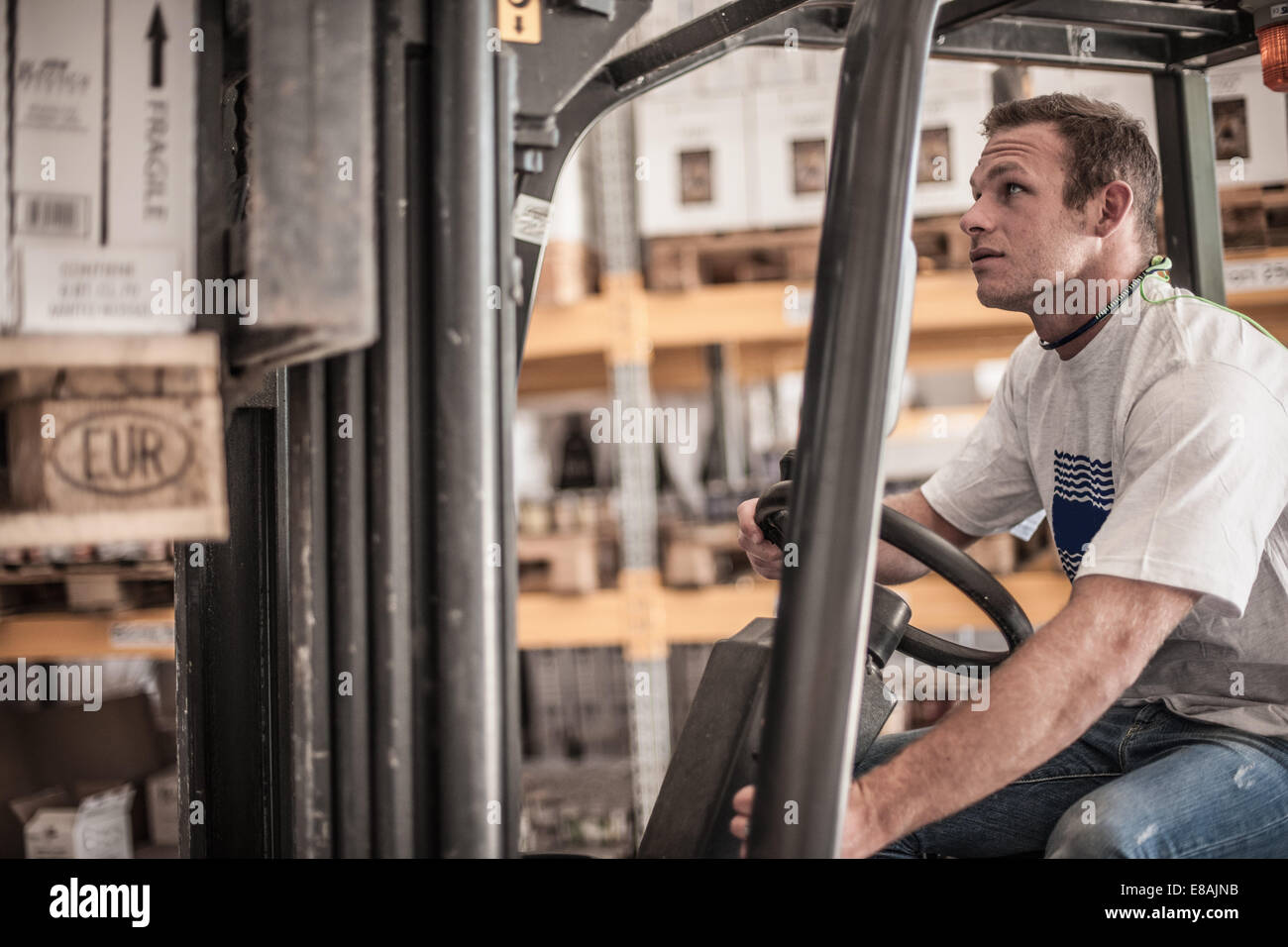 Jeune homme roulant chariot élévateur en usine-entrepôt Banque D'Images