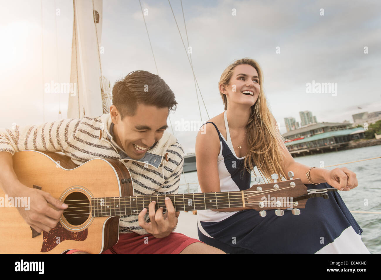 Jeune couple sur bateau à voile, man playing guitar Banque D'Images