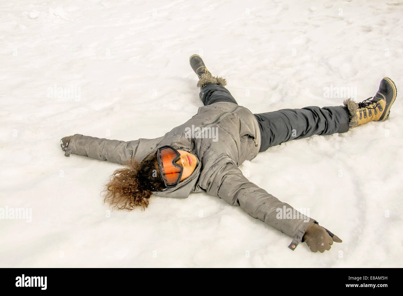 Jeune fille allongée sur le dos dans la neige Banque D'Images