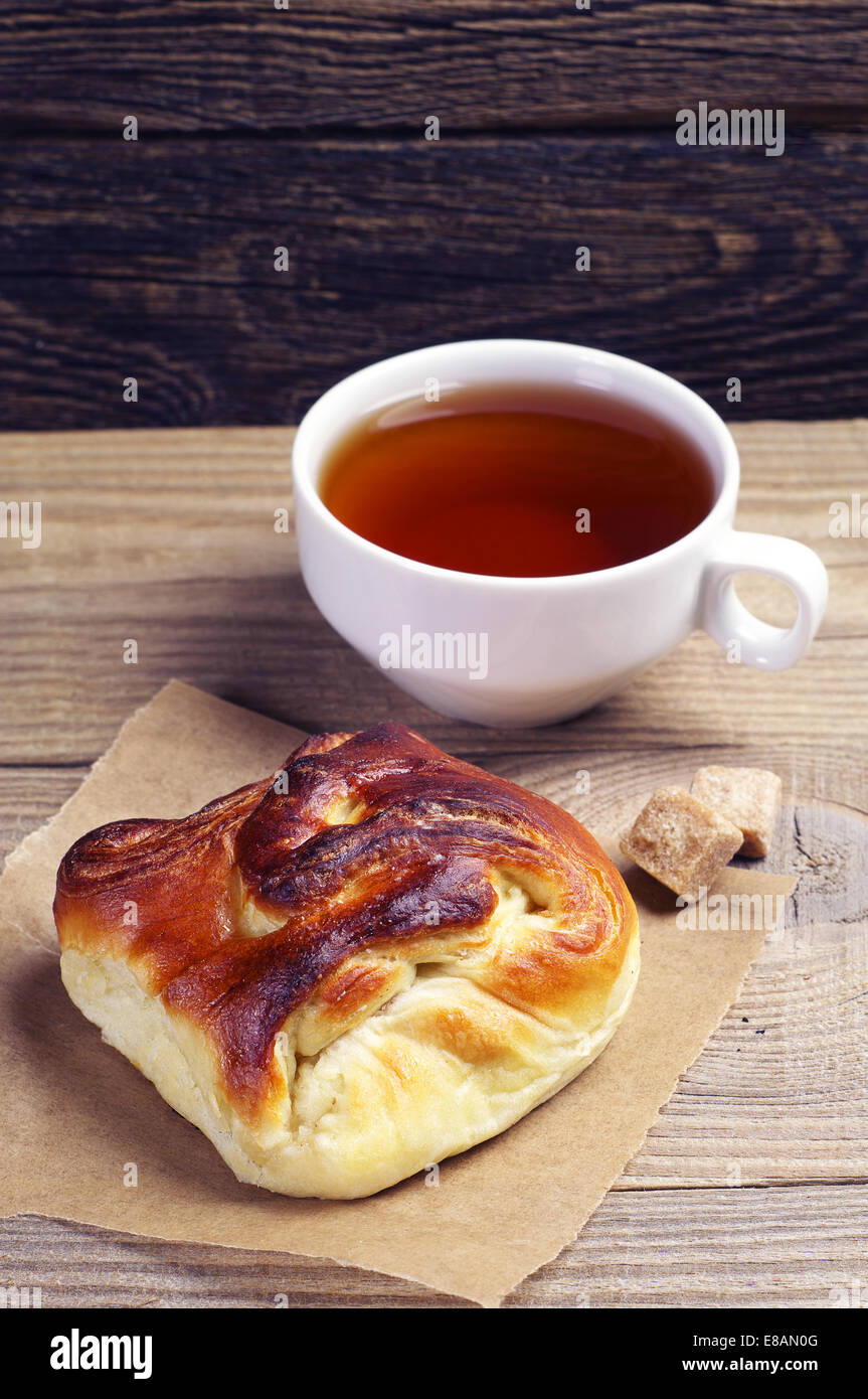 Petit pain sucré et une tasse de thé sur la table en bois Banque D'Images