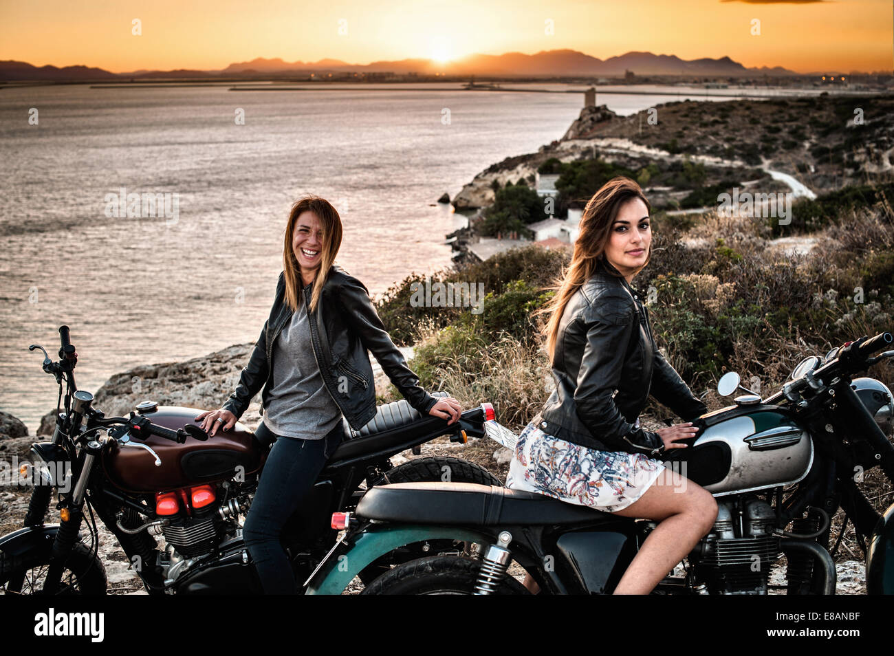 Portrait de deux femmes amis motocyclistes sur l'autre au coucher du soleil, Cagliari, Sardaigne, Italie Banque D'Images