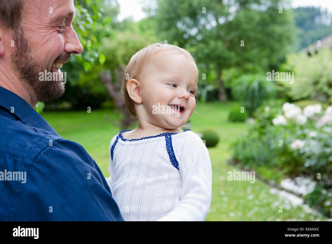 Father carrying baby daughter in garden Banque D'Images