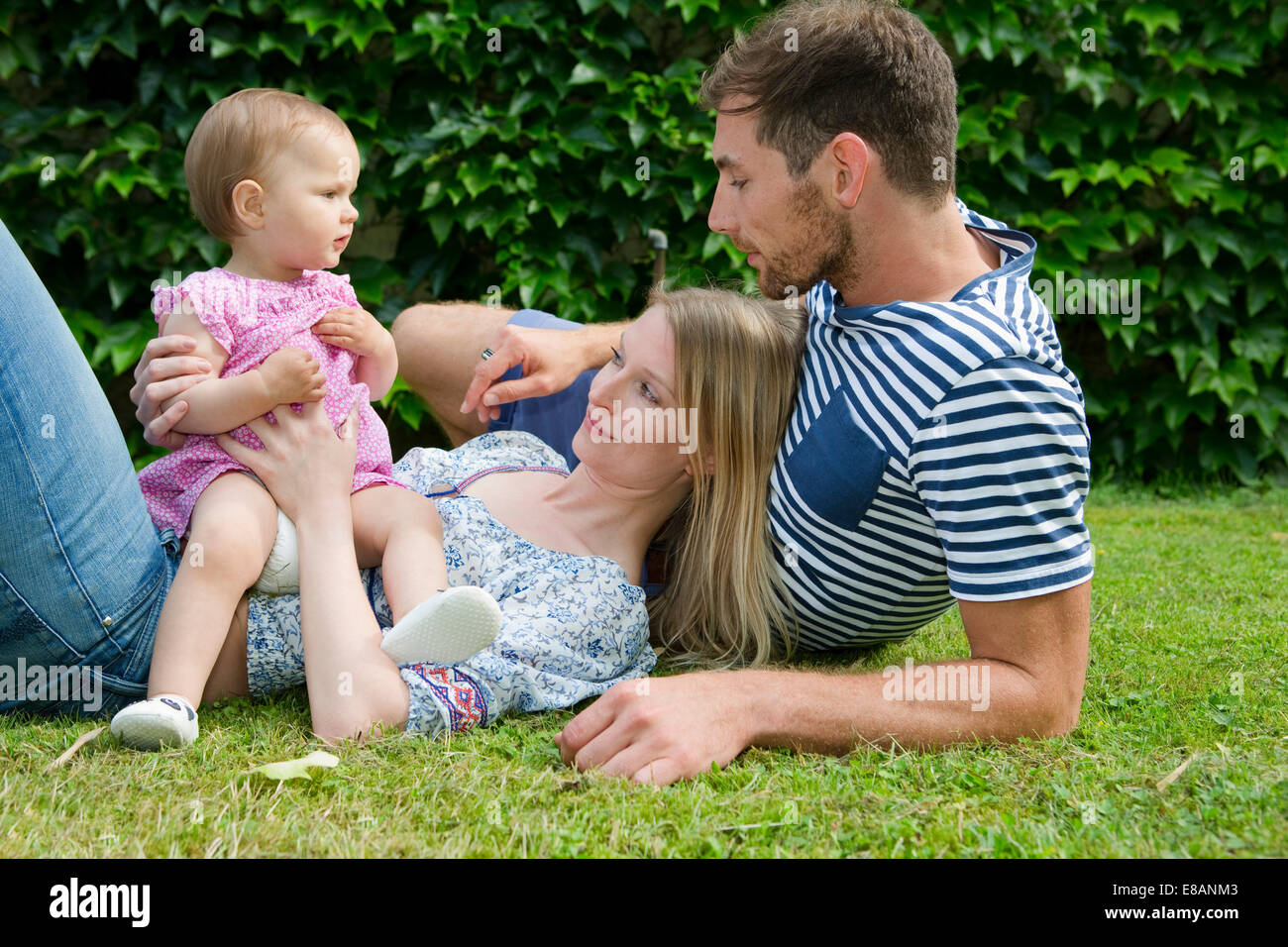 Couple avec bébé fille couchée sur pelouse au jardin Banque D'Images
