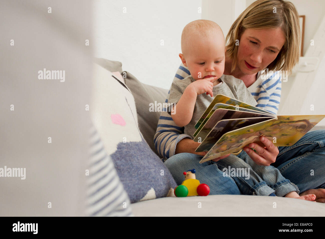Mère et bébé fille mature sur canapé salon lecture storybook Banque D'Images