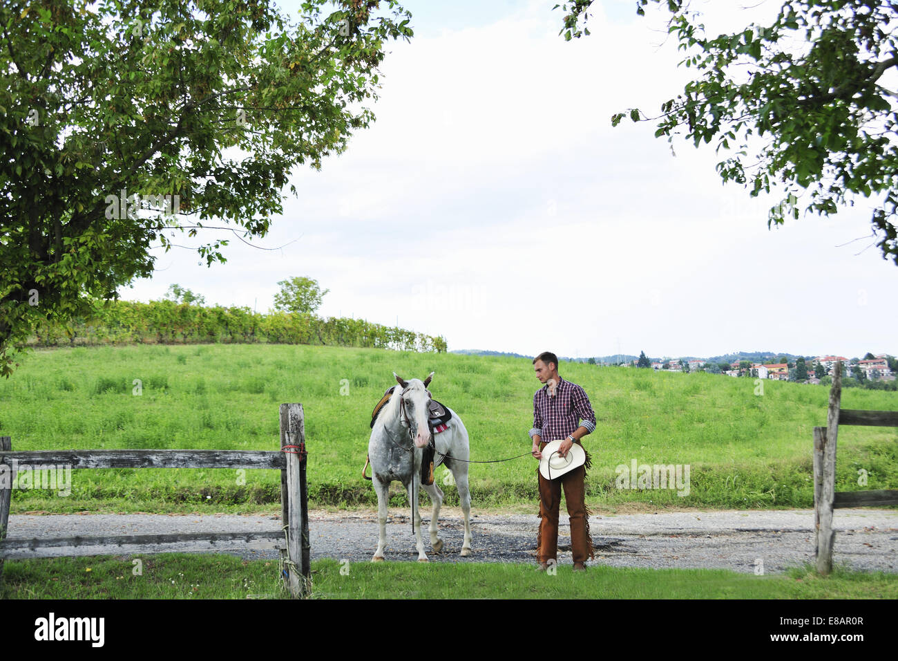 Jeune homme en menant du cowboy cheval dans gateway Banque D'Images