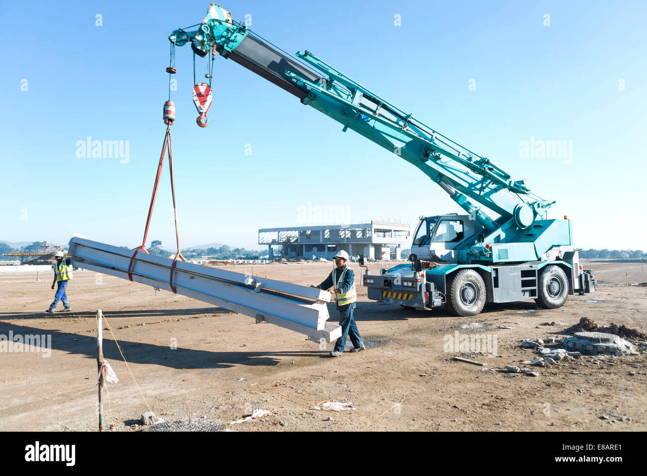 Deux constructeurs guider poutres sur crane at construction site Banque D'Images