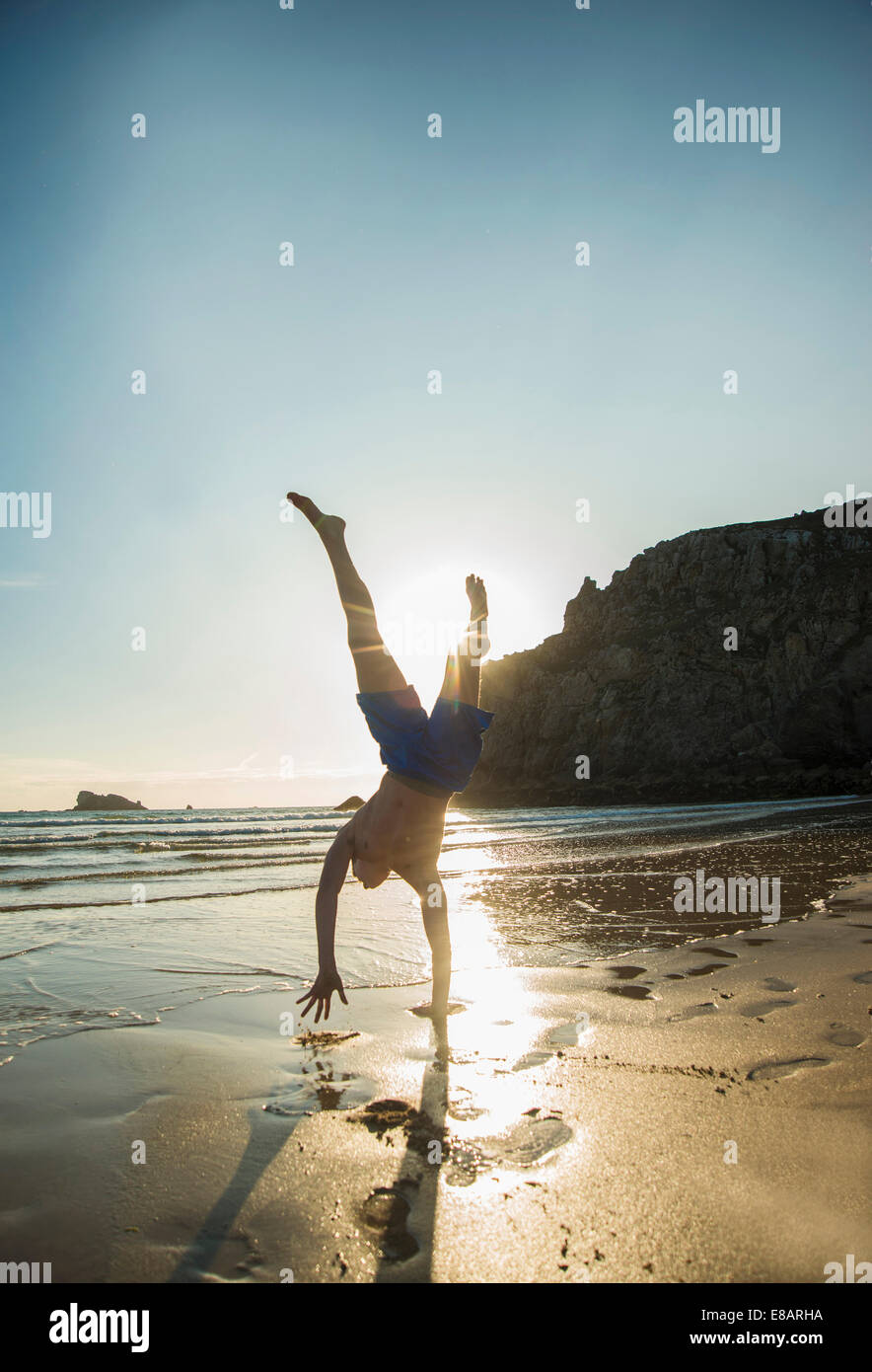 Teenage boy doing handstand at beach, Camaret-sur-mer, Bretagne, France Banque D'Images