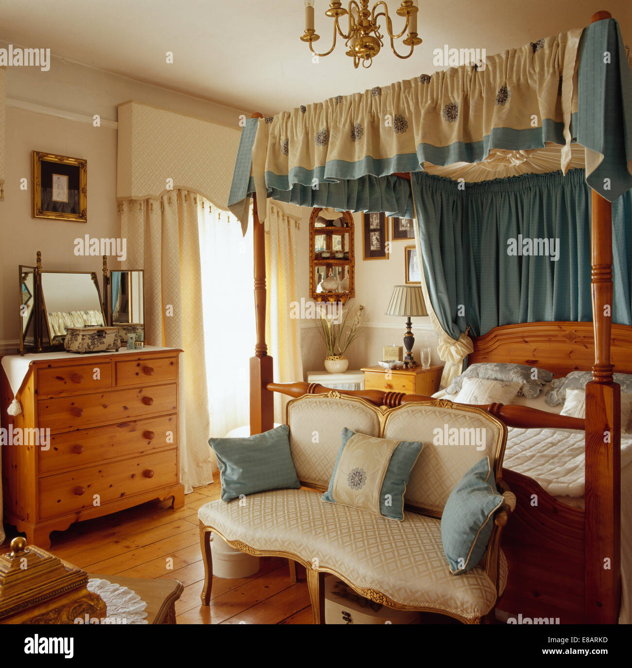 Les petits cadres dorés canapés rembourrés soie ci-dessous lit à baldaquin avec des rideaux en soie bleu +crème en appartement chambres Banque D'Images