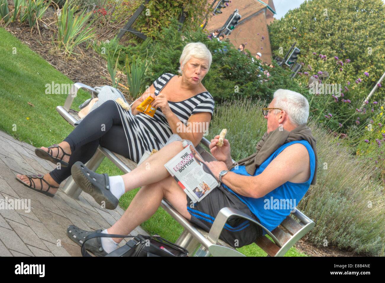 Deux personnes sur le banc de parc de manger Banque D'Images