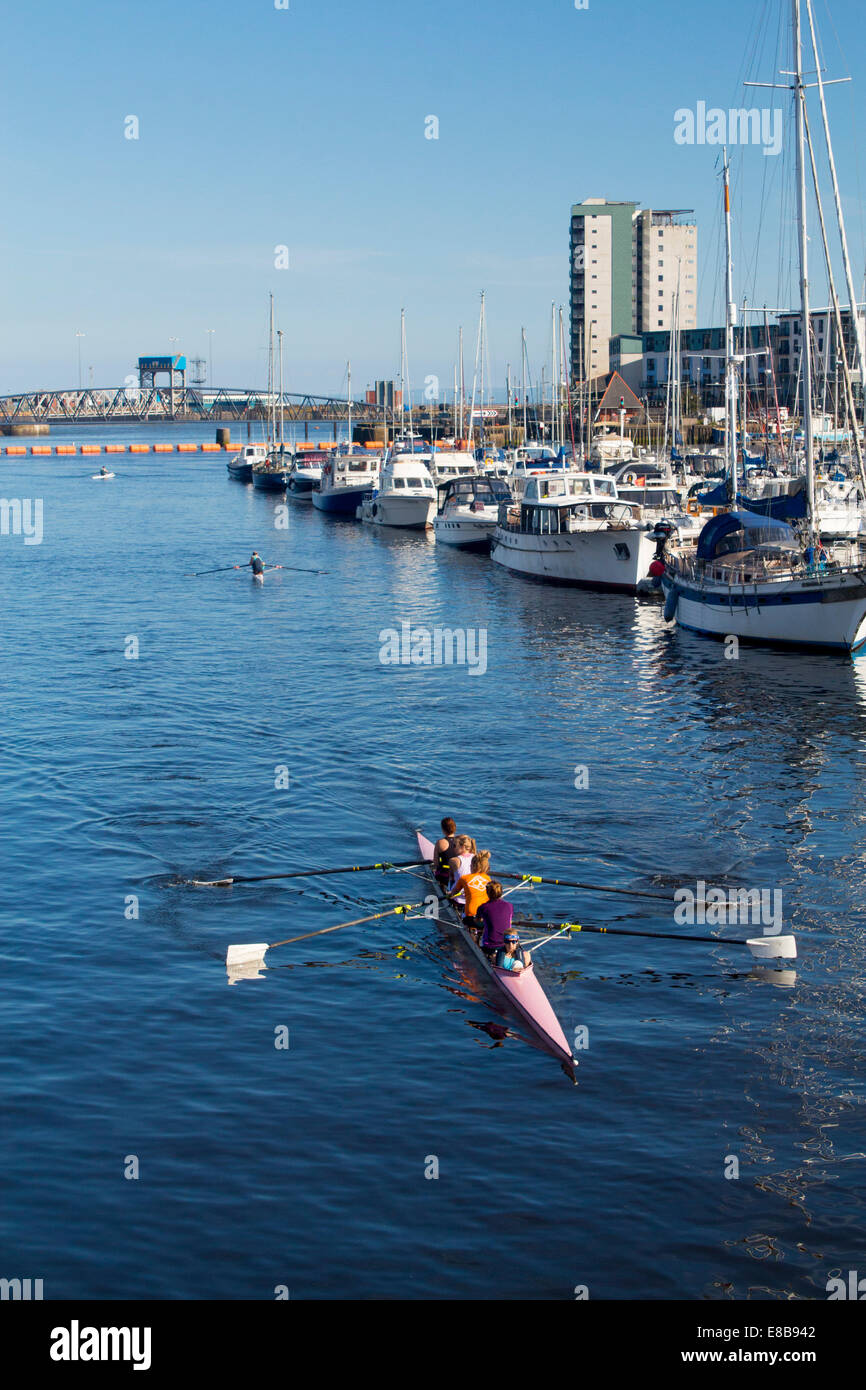 Équipage de quatre rameurs et barreur de cox en formation boat on river Tawe avec bateaux amarrés dans la Marina à droite de shot Maritime Banque D'Images