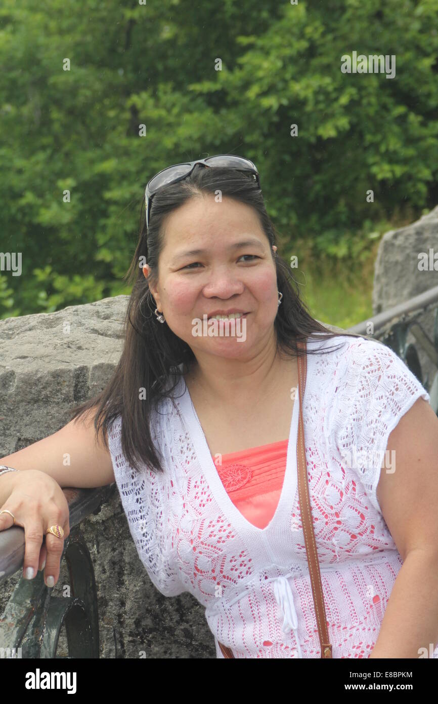 Jolie, Mature Asian woman leaning on a metal rambarde, posant pour des photos Banque D'Images