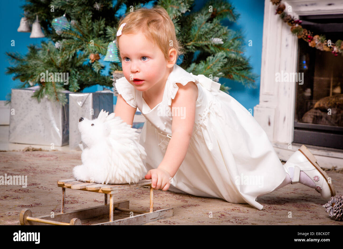 Petite fille dans une robe de fête joue près de l'arbre de Noël Banque D'Images