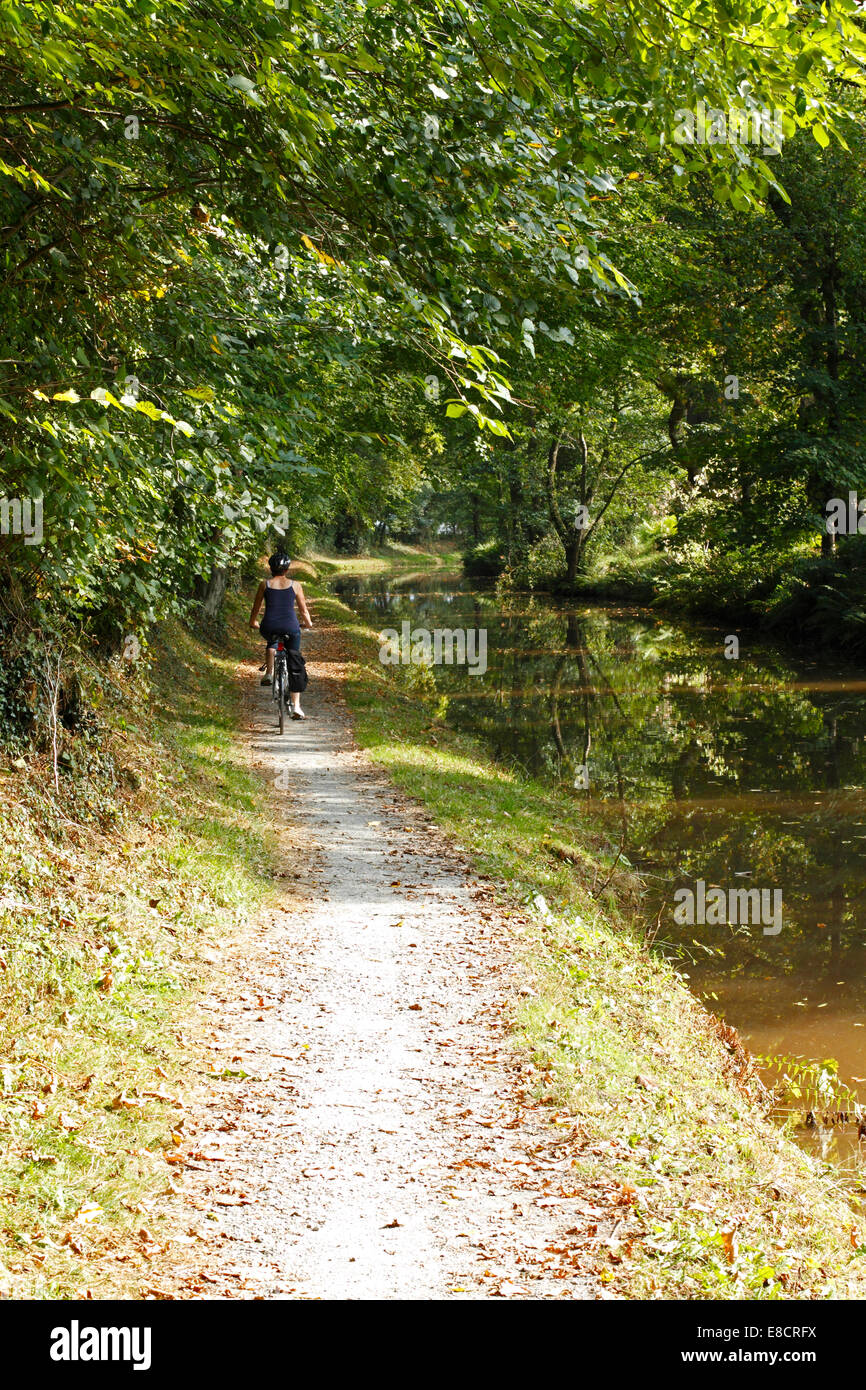 Jeune femme à vélo sur un chemin de halage du canal Banque D'Images