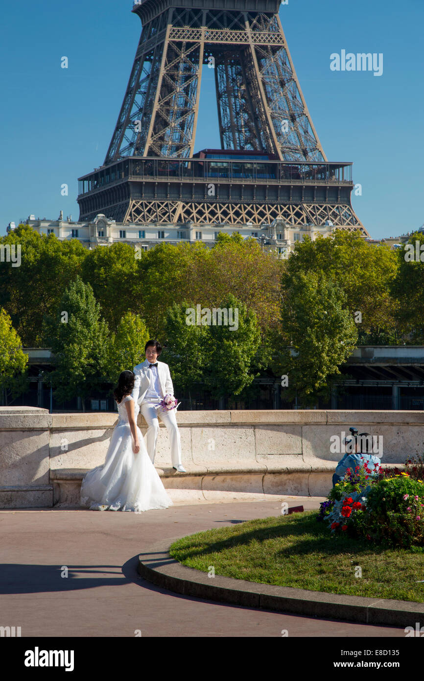 Wedding couple pose pour les photos ci-dessous de la Tour Eiffel, Paris, France Banque D'Images