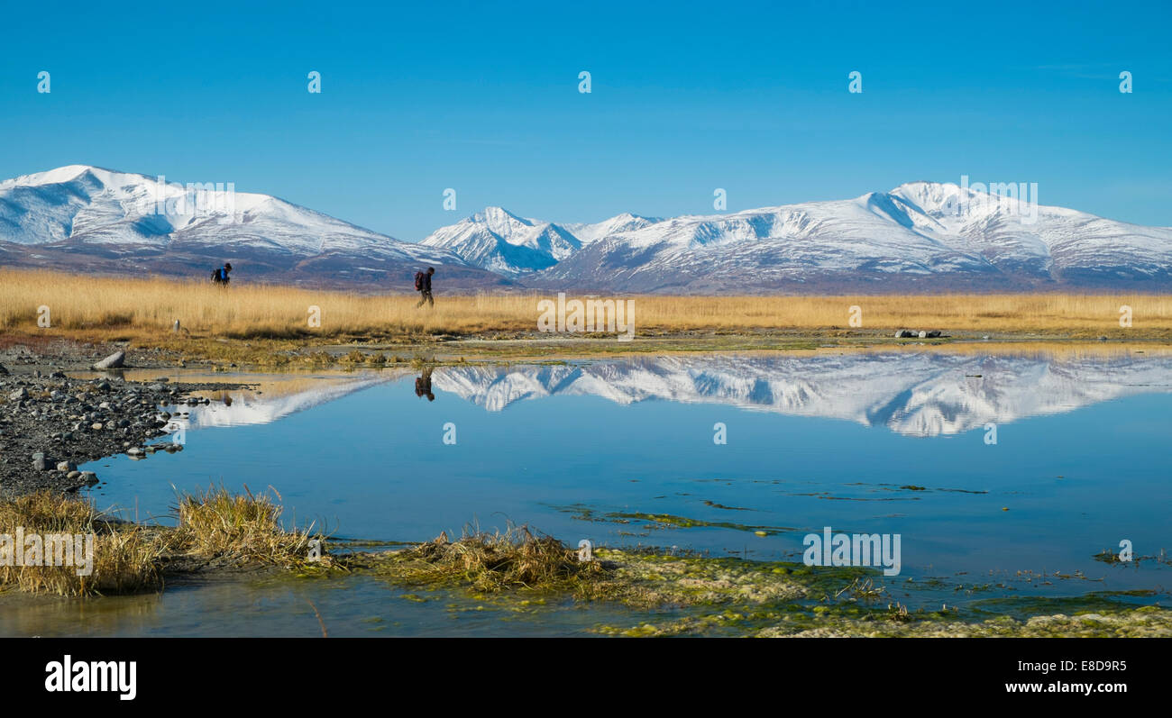 Randonneurs à Khurgan Nuur, reflété dans le lac en face de montagnes de l'Altaï, région limitrophe de la Chine Banque D'Images