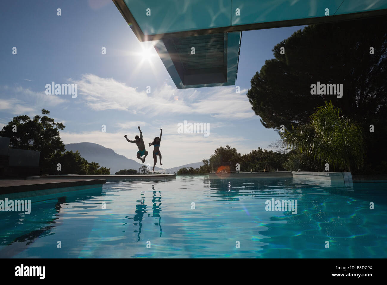 Cheerful young couple jumping into swimming pool Banque D'Images