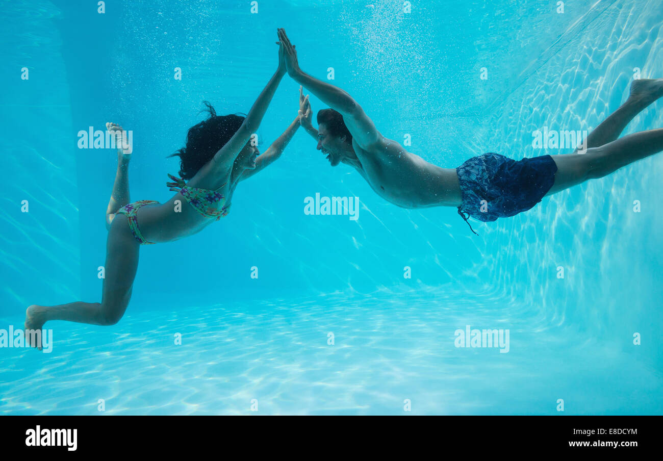 Couple holding hands and swimming underwater Banque D'Images