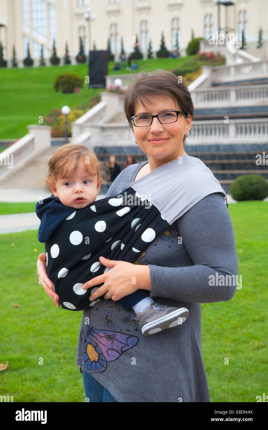 Portrait de mère portant son bébé garçon dans un harnais dans le parc. Banque D'Images