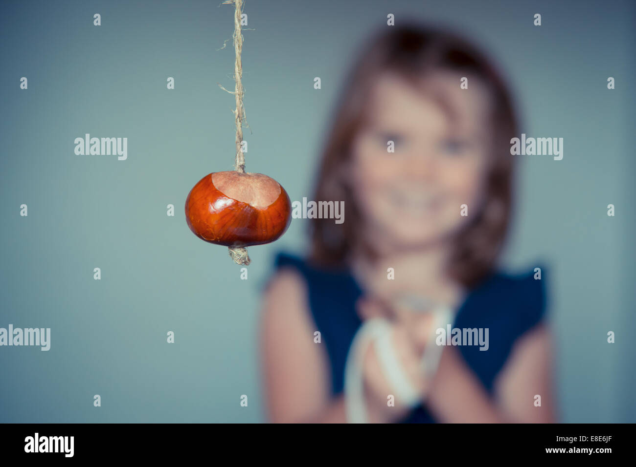Une jeune fille jouer conkers avec un fond uni. Banque D'Images