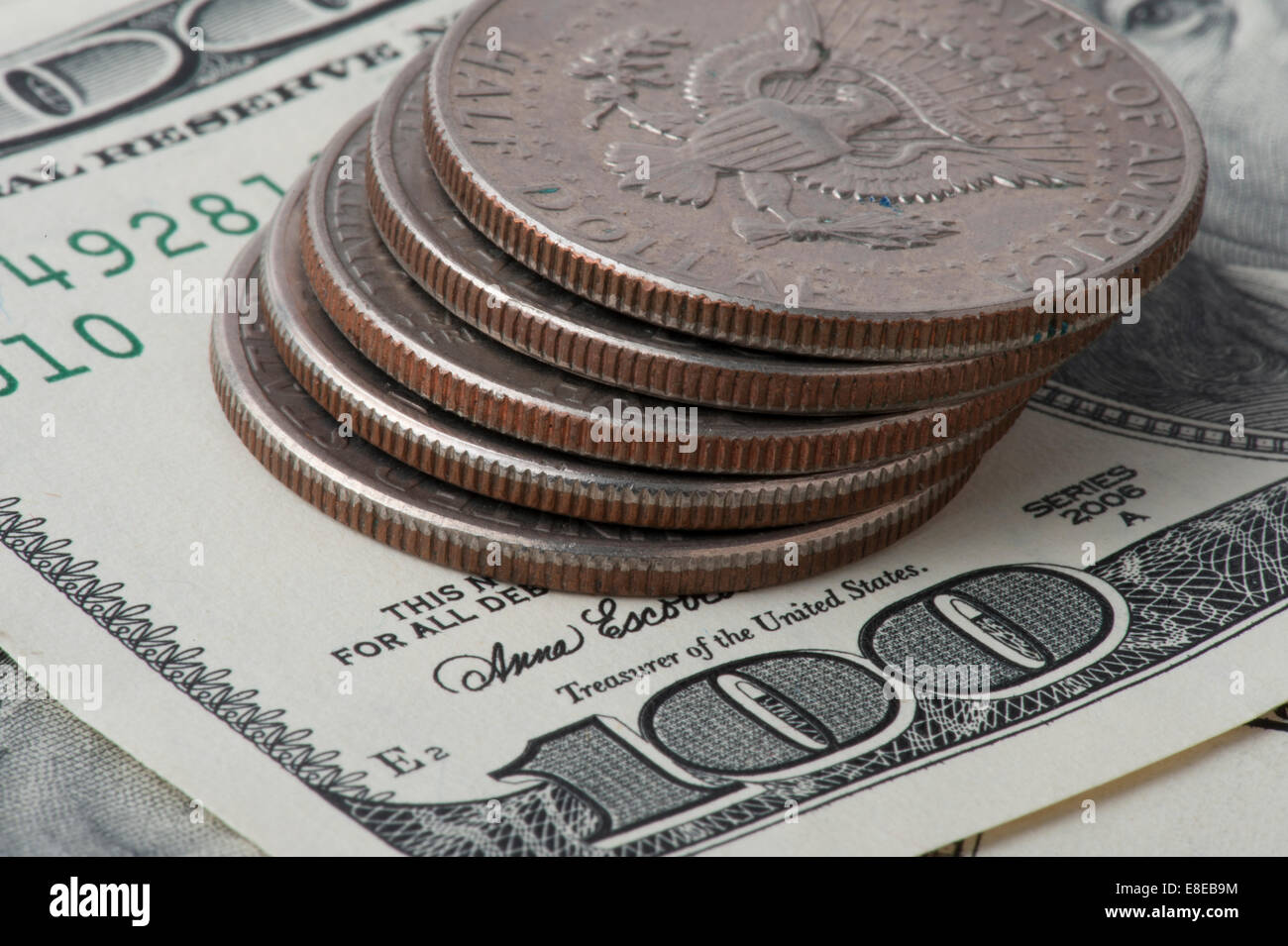 Cinq demi-dollar pièces empilées sur $100 dollar bills Banque D'Images