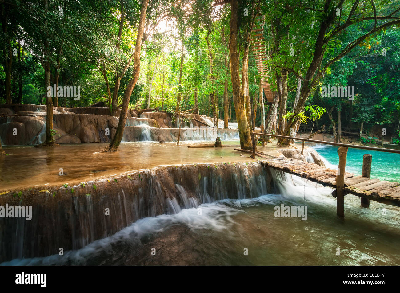 Jangle paysage de forêt tropicale humide paysage avec pont de bois et de l'eau turquoise magnifique cascade de Kuang Si waterfall. Banque D'Images Jangle paysage de forêt tropicale humide paysage avec pont de bois et de l'eau turquoise magnifique cascade de Kuang Si waterfall. Banque D'Images