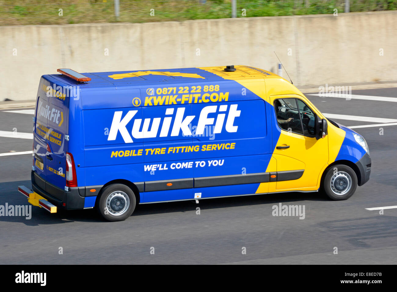 Vue latérale de la publicité pour le montage de pneus mobiles d'affaires Kwik Fit sur un minibus bleu jaune voyageant le long de l'autoroute britannique Banque D'Images
