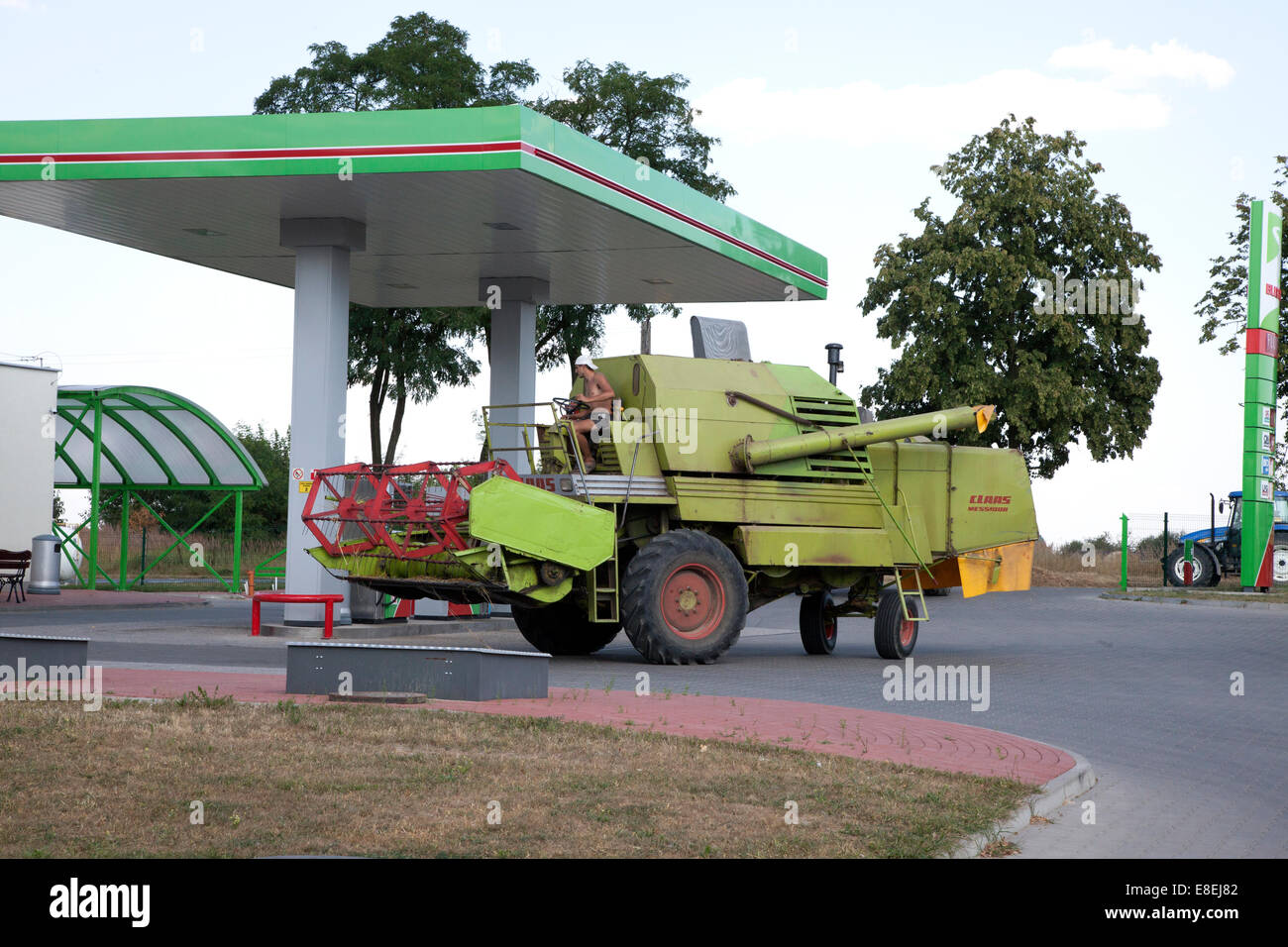 La conduite d'un agriculteur ferme la moissonneuse-batteuse, dans une station-service pour faire le plein. Rzeczyca Pologne Banque D'Images