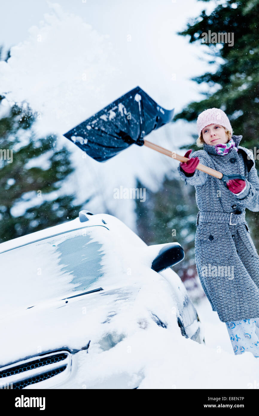Voiture prise dans la neige et d'une femme après une grosse tempête de neige à pelleter Banque D'Images