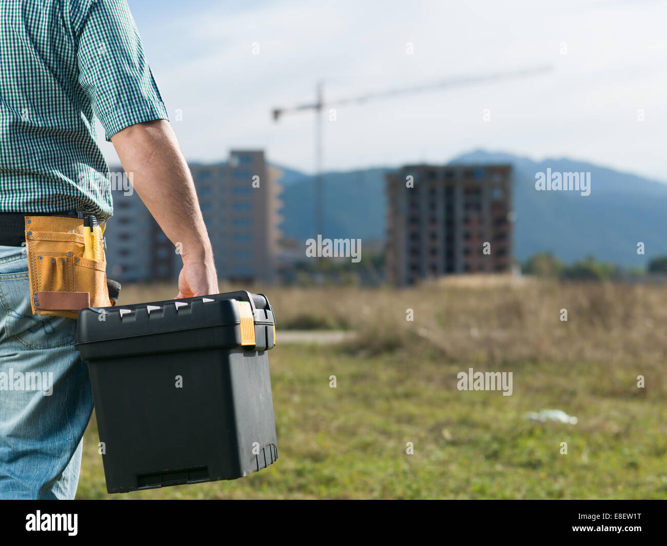 Gros plan, vue arrière de l'ingénieur homme debout sur l'extérieur du site de construction, outil de maintien fort Banque D'Images Gros plan, vue arrière de l'ingénieur homme debout sur l'extérieur du site de construction, outil de maintien fort Banque D'Images