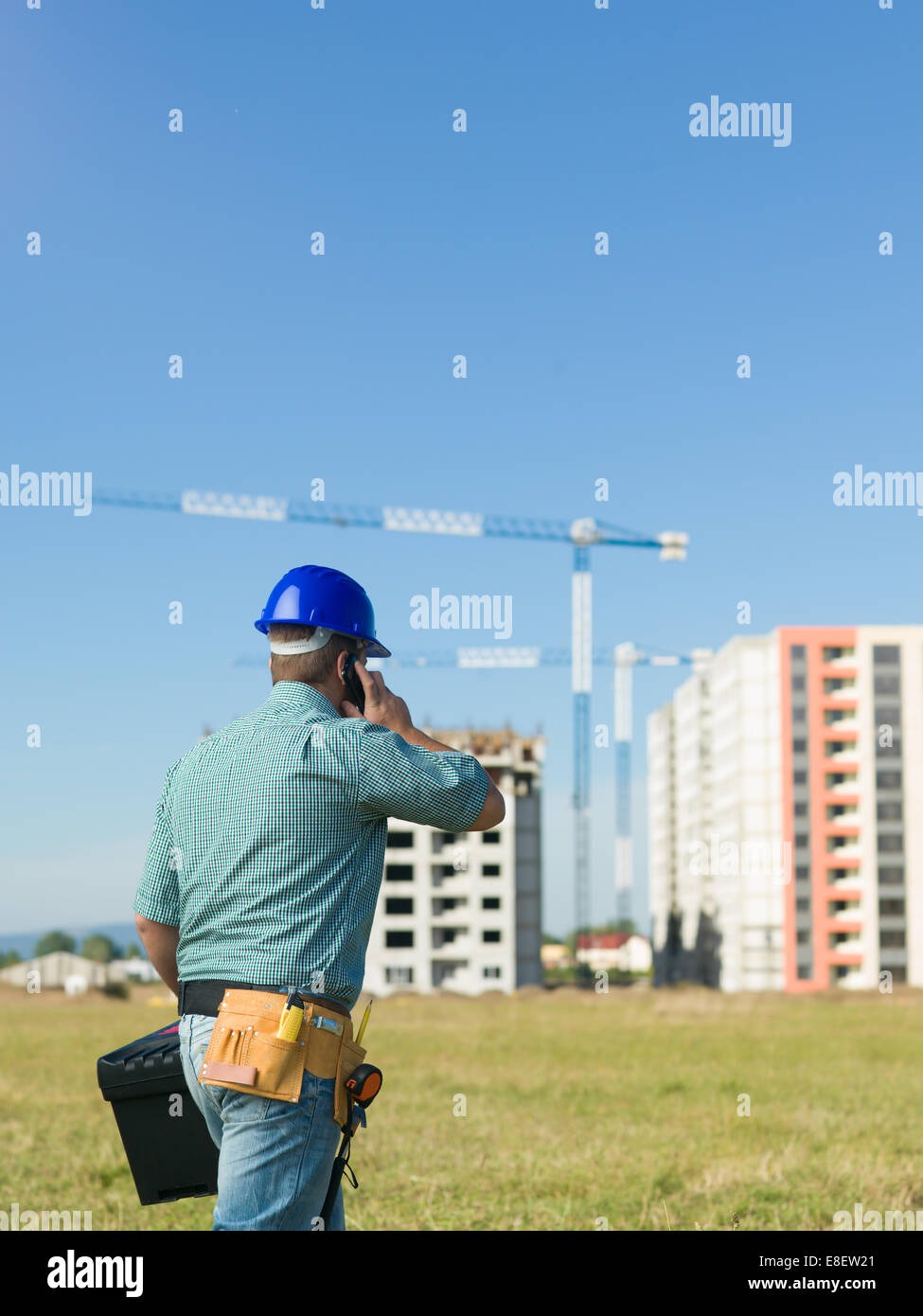 Vue arrière de l'ingénieur d'hommes parlant au téléphone au site de construction résidentielle Banque D'Images