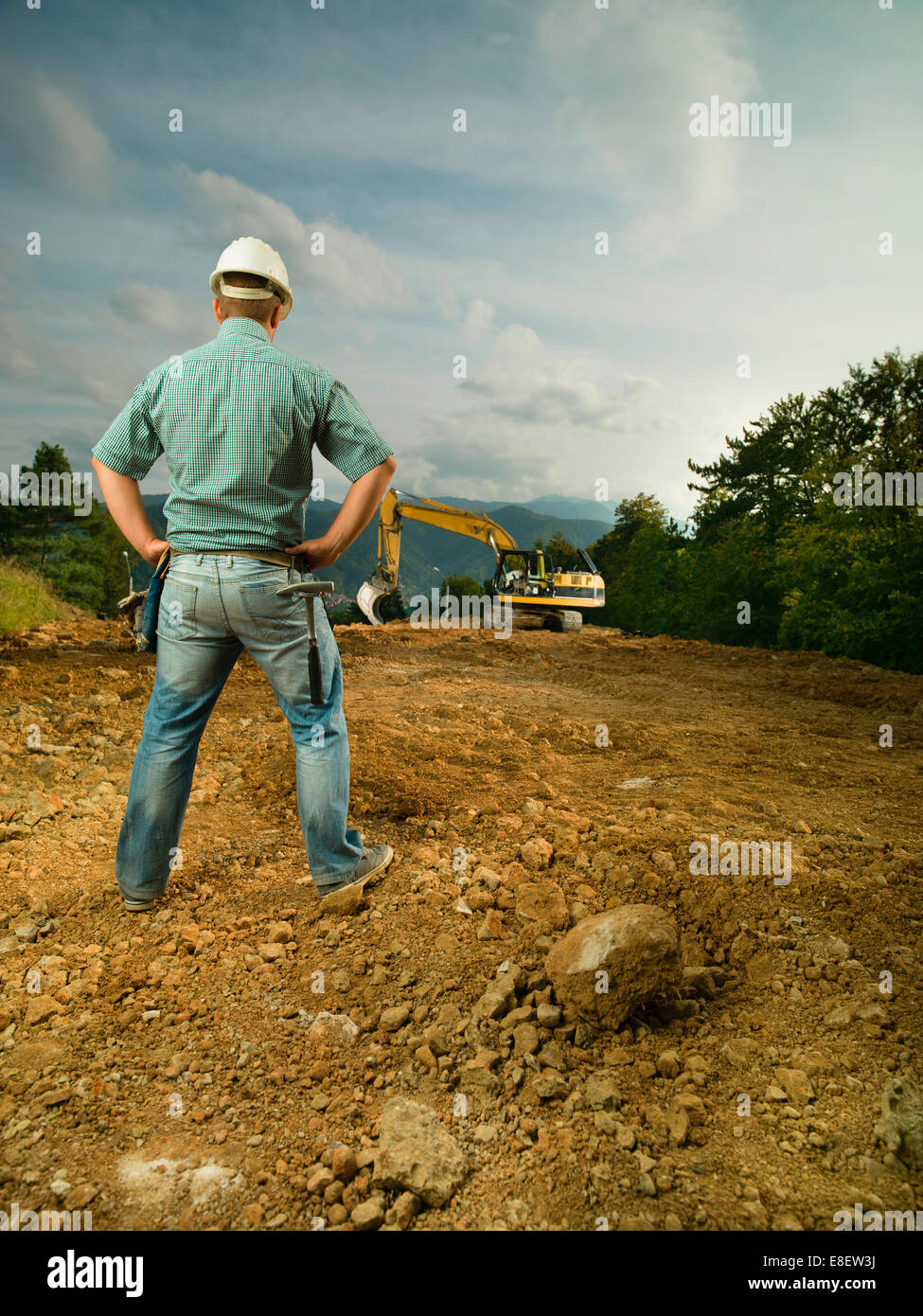 Vue arrière de l'ingénieur mâle debout sur chantier de l'évaluation des progrès Banque D'Images Vue arrière de l'ingénieur mâle debout sur chantier de l'évaluation des progrès Banque D'Images