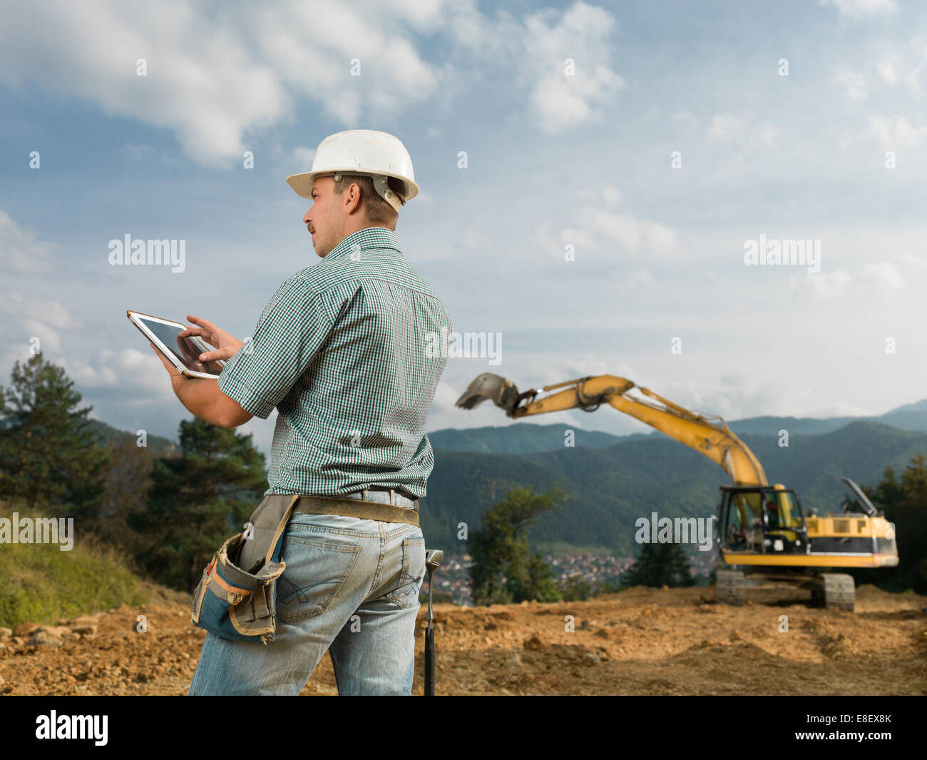 Vue arrière de l'ingénieur de race blanche debout sur chantier la navigation sur tablette numérique Banque D'Images Vue arrière de l'ingénieur de race blanche debout sur chantier la navigation sur tablette numérique Banque D'Images