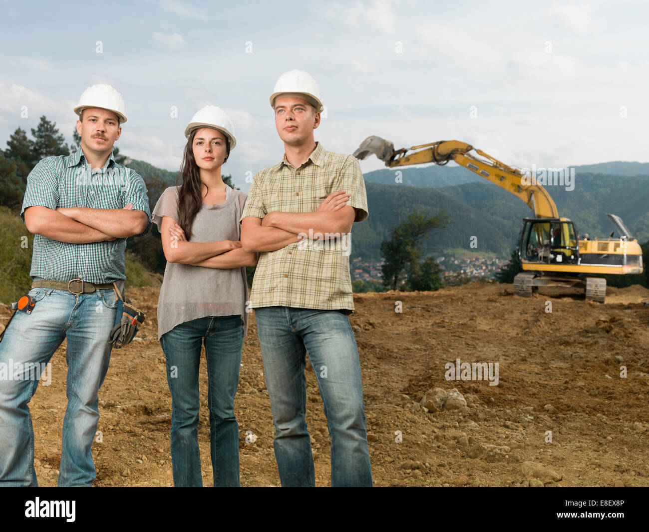 Groupe de trois architectes de race blanche debout, les bras croisés sur l'extérieur du site de construction Banque D'Images Groupe de trois architectes de race blanche debout, les bras croisés sur l'extérieur du site de construction Banque D'Images