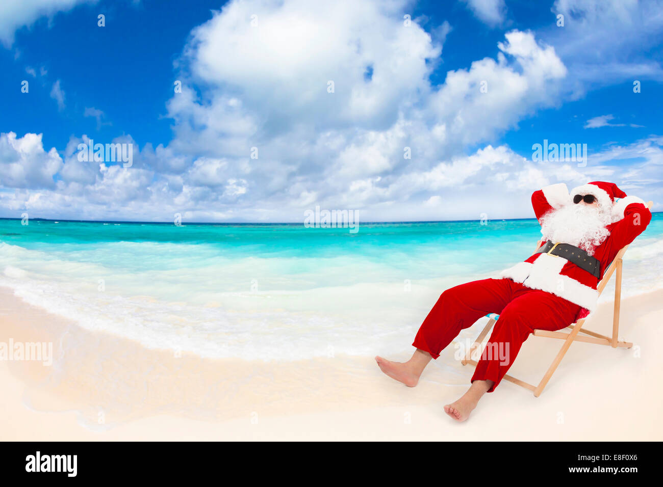 Père Noël assis sur des chaises de plage avec ciel bleu et de nuages. Concept de vacances de Noël. Banque D'Images