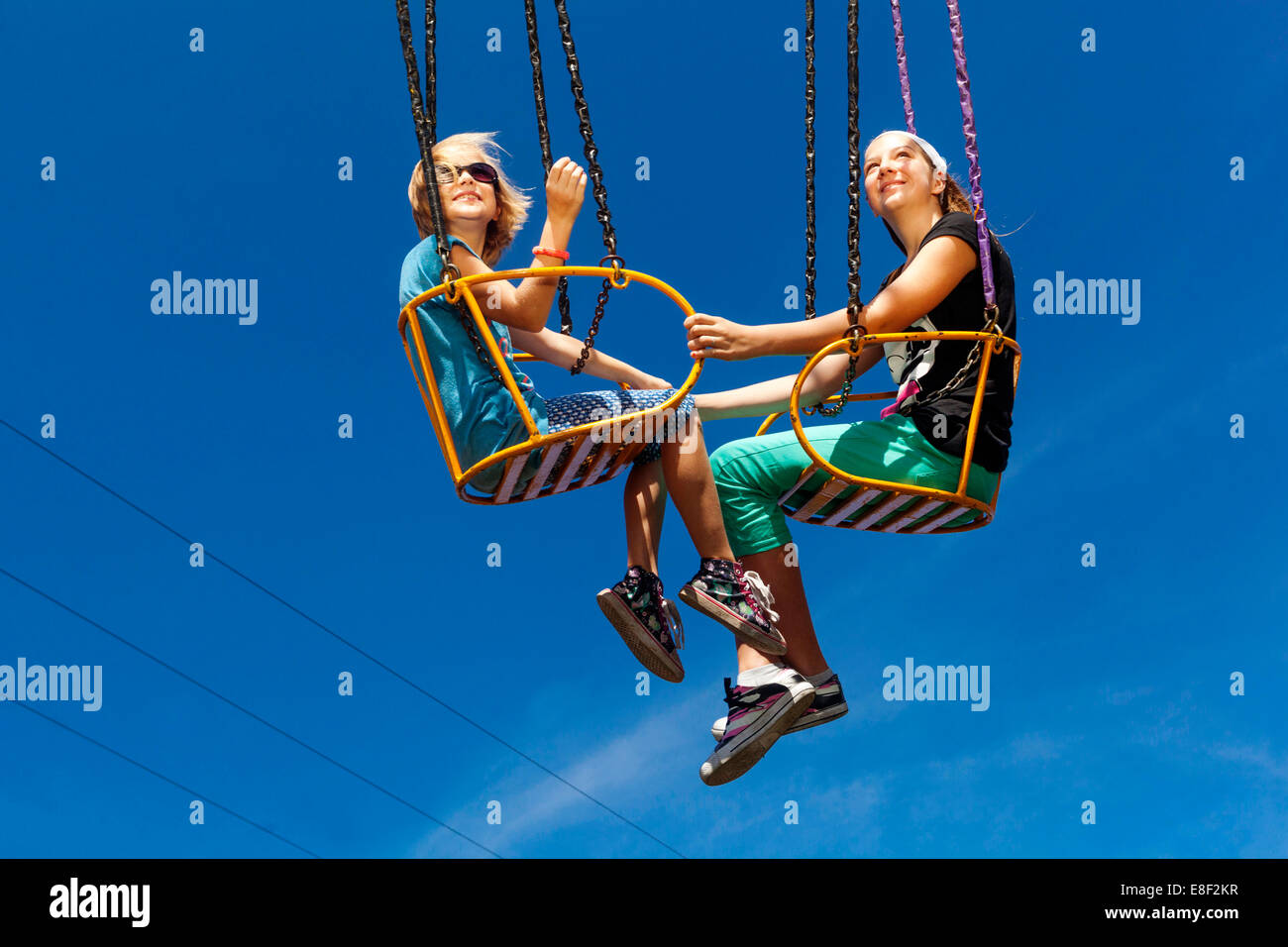 Adolescents deux filles sur le carrousel d'oscillation de chaîne Banque D'Images