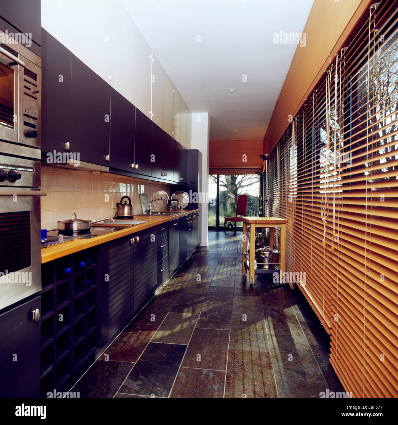 Sol en ardoise et les stores vénitiens en bois dans la cuisine moderne avec des plateaux sur les unités noir Banque D'Images