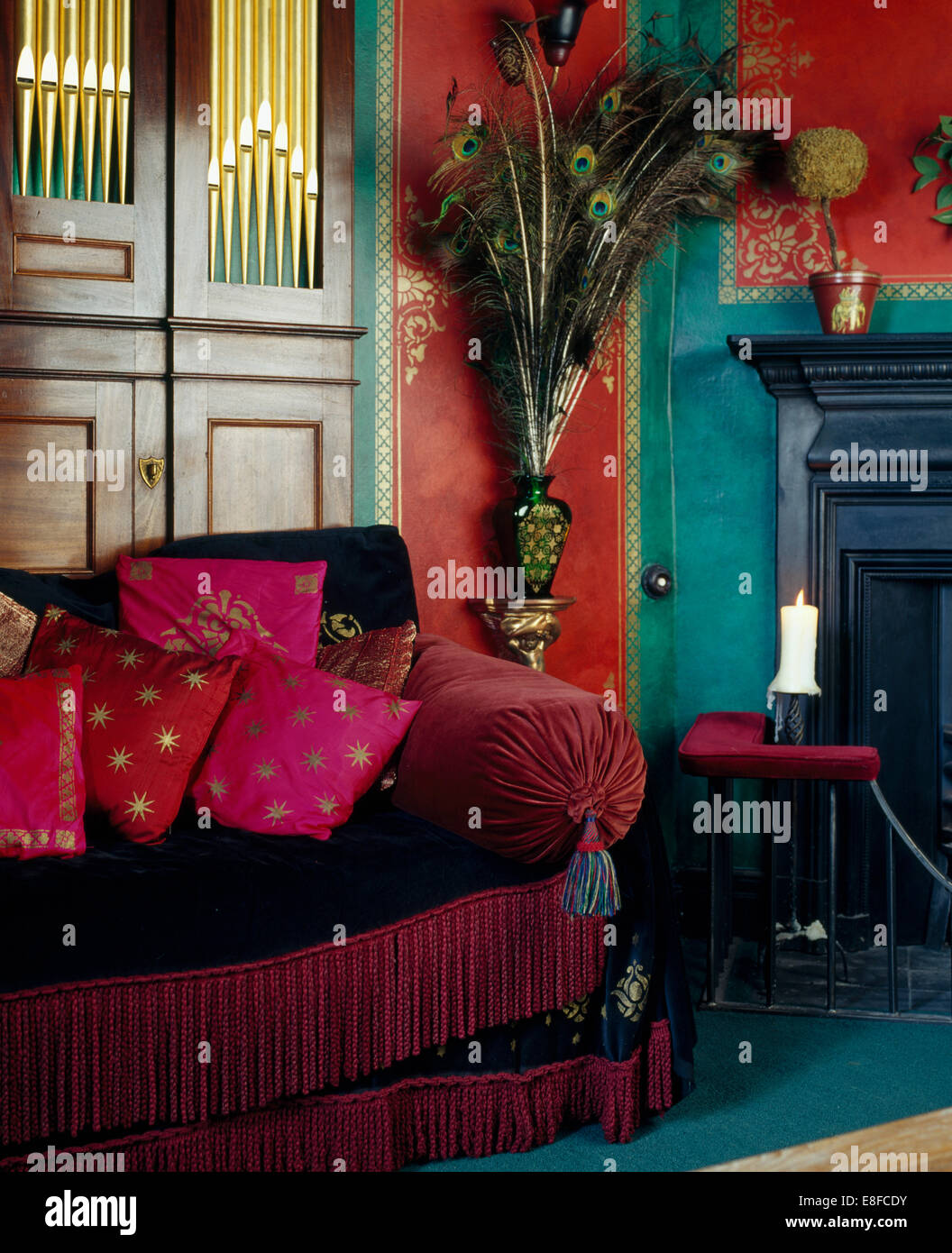 Rose au pochoir sur des coussins de velours rouge canapé en rouge salon avec placard et murs au pochoir d'or Banque D'Images