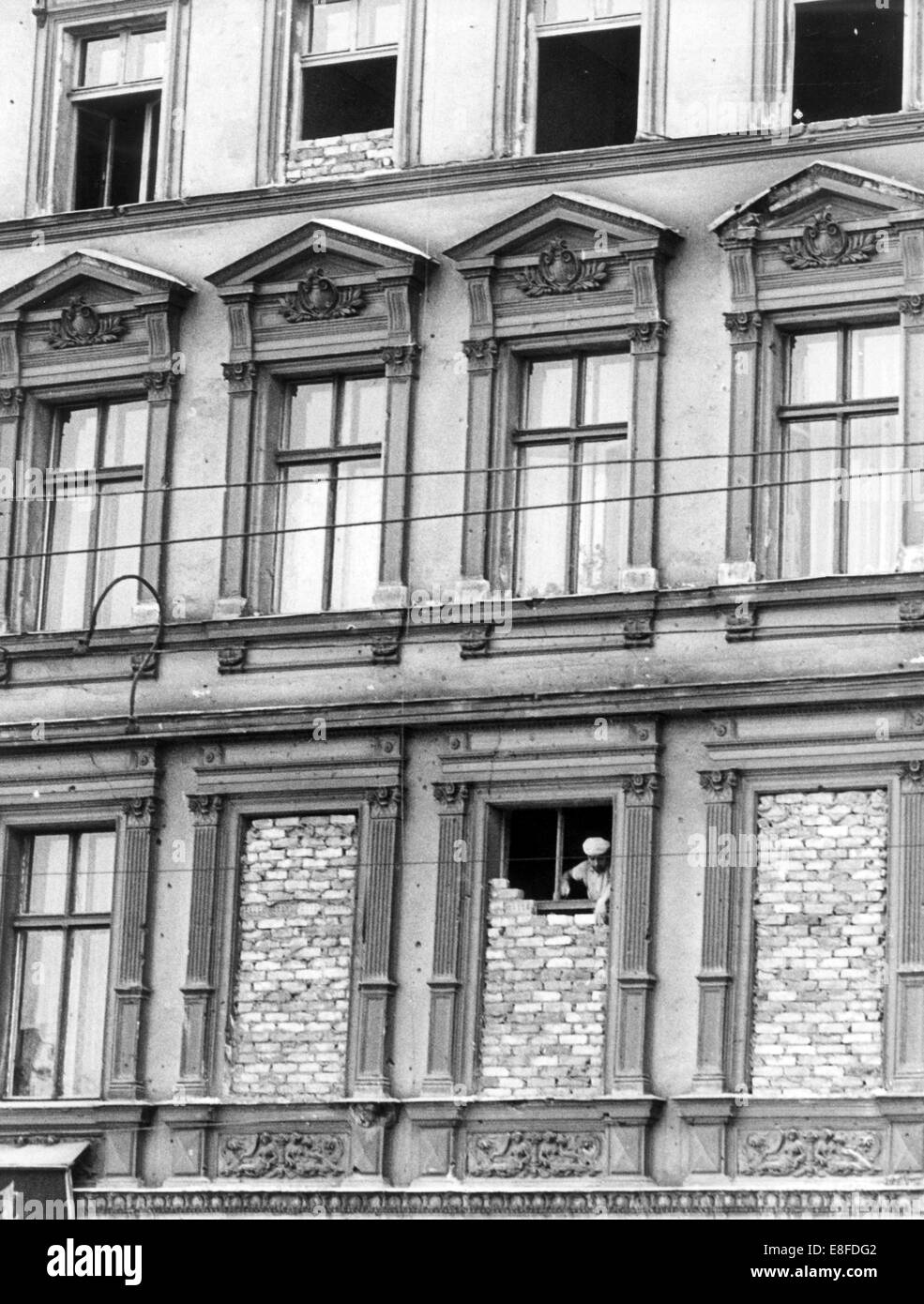 Une couche de brique de la RDA fonctionne sur une fenêtre, qui n'a pas encore été complètement murée, dans une maison en bordure de la rue Bernauer à Berlin le 1er octobre en 1961. Banque D'Images