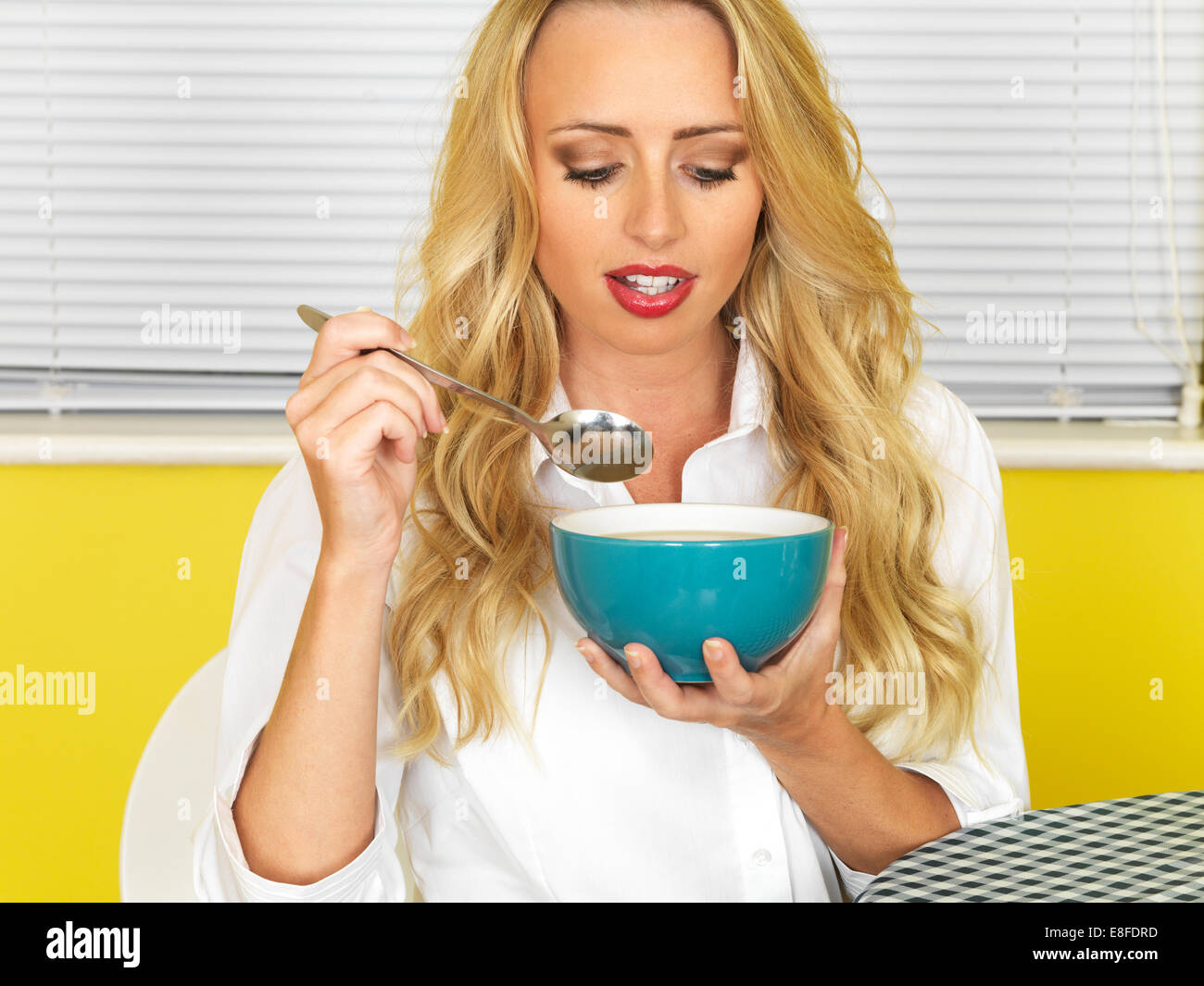 Confident Happy Young Woman, manger un bol de soupe nourrissante chaude, sur fond jaune Banque D'Images